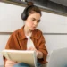 Mulher estudando com fones de ouvido e notebook, utilizando tecnologia para otimizar o aprendizado