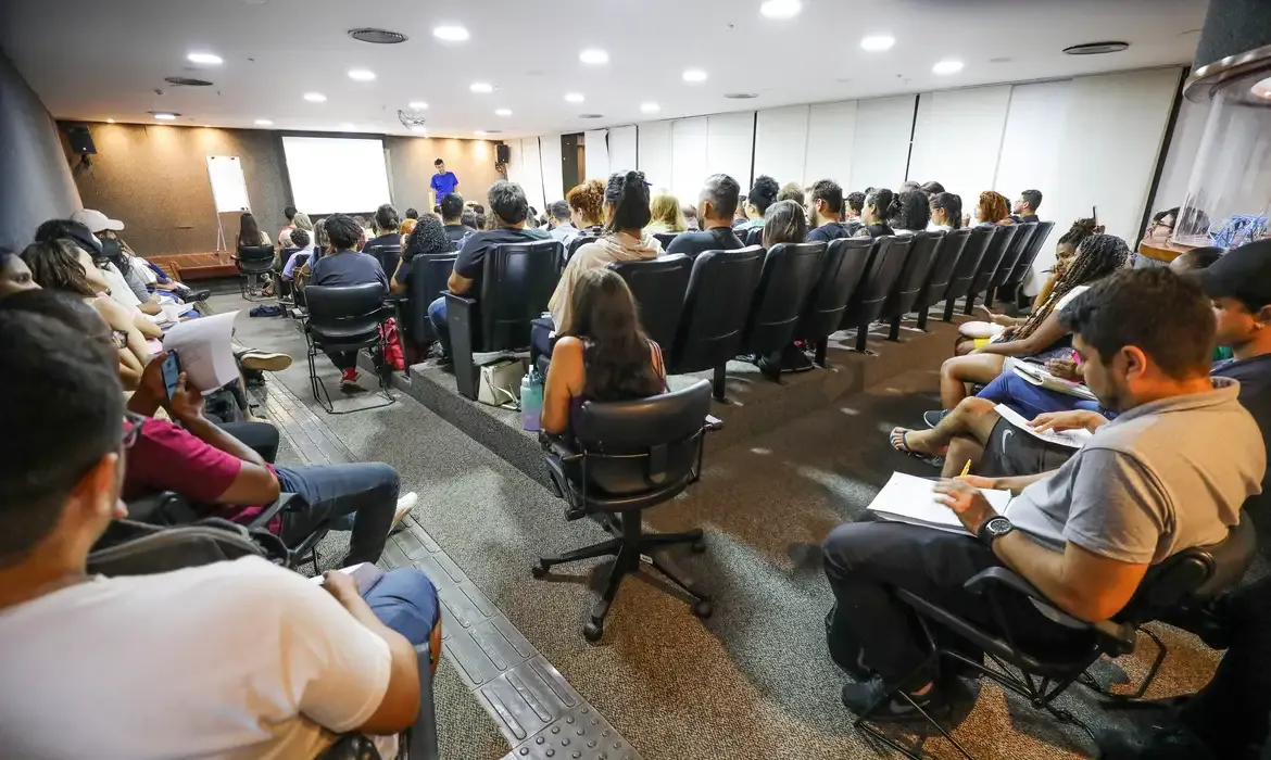 Aula preparatória para concurso público Sala de aula com candidatos assistindo a uma palestra preparatória para concurso público.