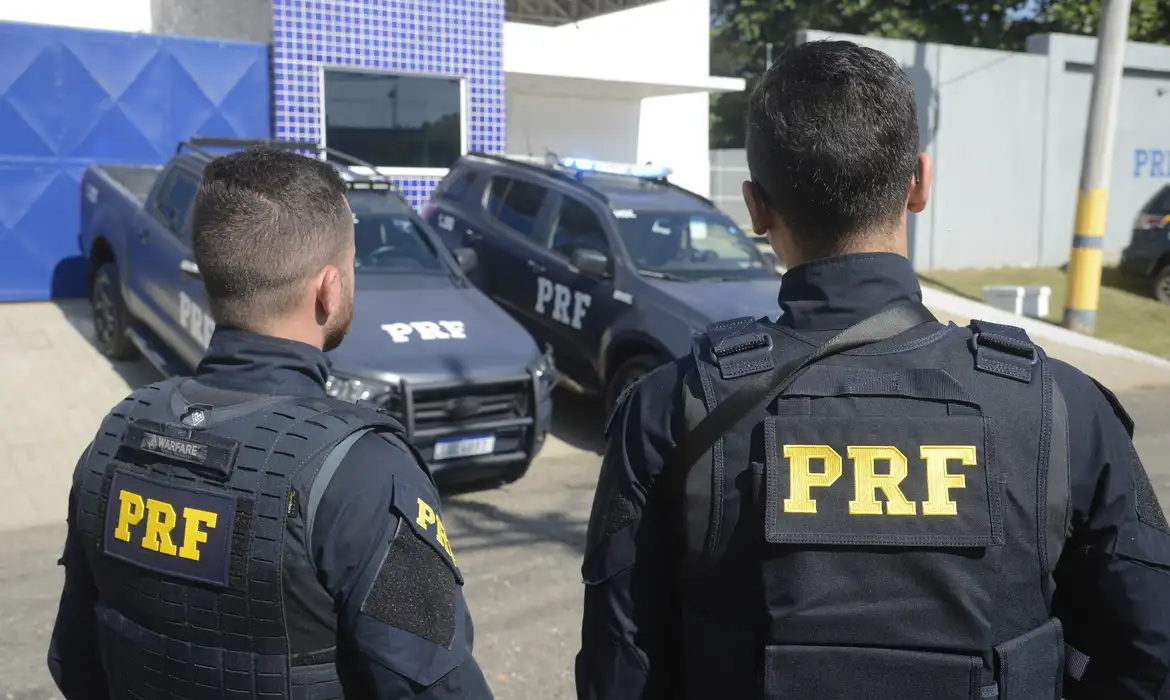 Requisitos para o Cargo de Policial Rodoviário Federal Policial Rodoviário Federal de costas, com viaturas ao fundo, representando os requisitos para o cargo de PRF.
