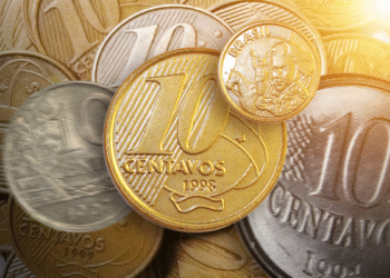 Moeda brasileira de 10 centavos de 1998 destacada em primeiro plano, cercada por outras moedas antigas