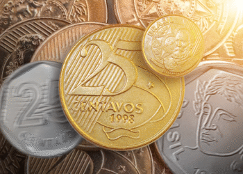 Moeda de 25 centavos do Plano Real em destaque, com outras moedas ao fundo, representando peças valiosas para colecionadores.