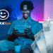 Homem sorrindo ao usar aplicativo Caixa Tem no tablet com cédulas ao fundo