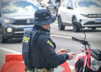 Agente da PRF fiscaliza documentos de motociclista.