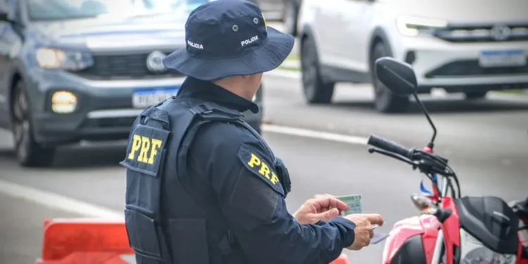Agente da PRF fiscaliza documentos de motociclista.