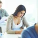 Estudantes em sala de prova respondendo questões de forma concentrada.