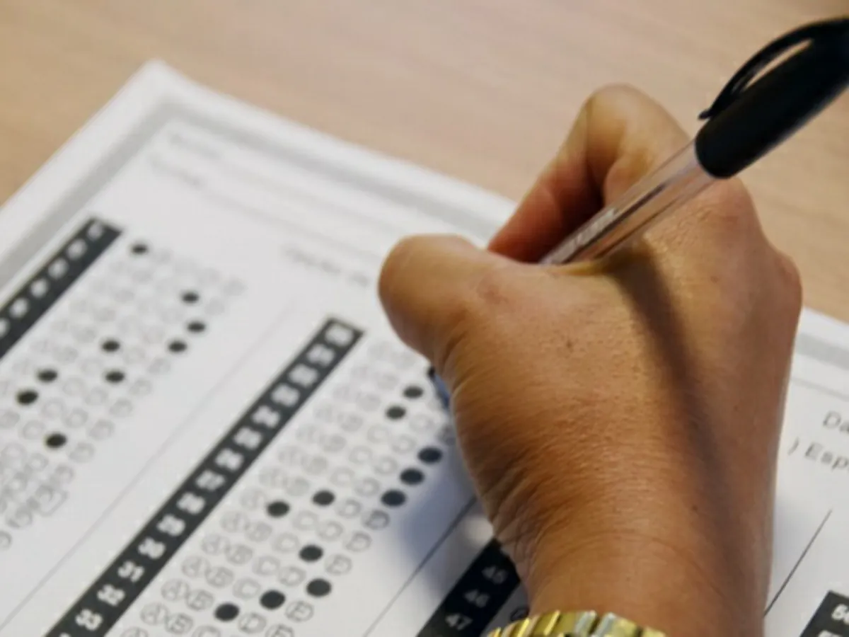 Pessoa preenchendo cartão-resposta durante prova de concurso