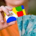 Mão segurando cartão do Bolsa Família ao lado de notas de 100 reais brasileiras.