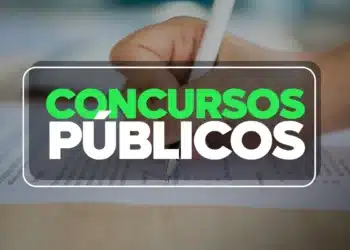 Pessoa preenchendo folha de prova de concurso público com caneta sobre mesa