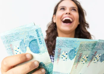 Pessoa sorrindo e segurando notas de 100 reais, simbolizando conquistas financeiras e bons negócios.