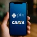Imagem de um celular com tela mostrando o logo do Pix e da Caixa Econômica Federal, relacionada à divulgação de pagamento do PIX de R$ 1.108