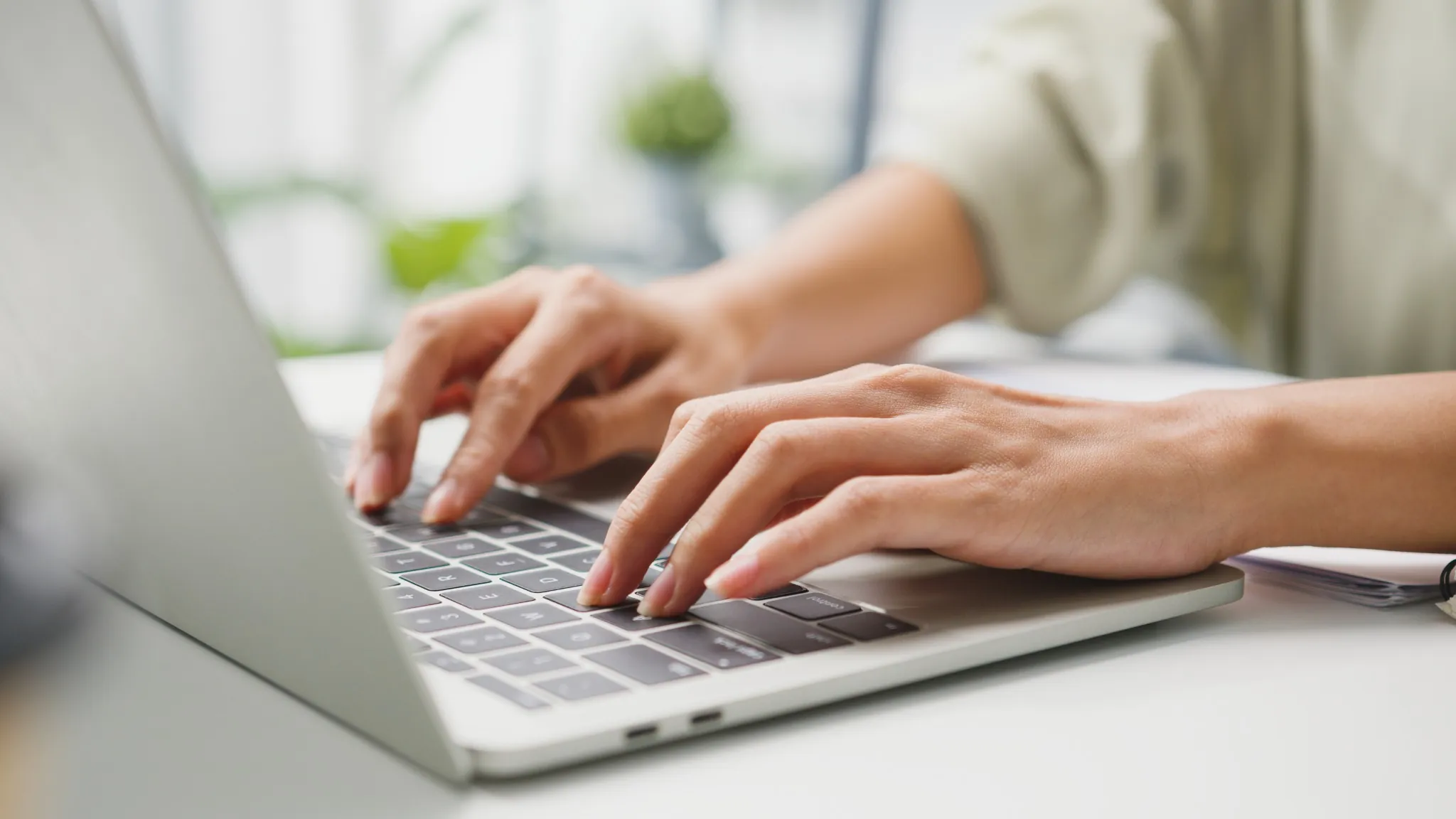 Mãos digitando em teclado de notebook