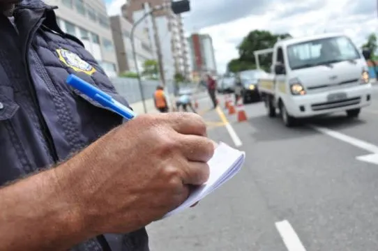 Policial escrevendo multa de trânsito em bloco de notas