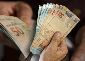Mão segurando cédulas de real em diferentes valores
