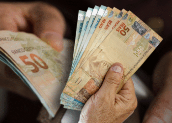 Imagem de mãos segurando notas de reais, ilustrando o pagamento do 13º salário.