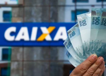 Nota de 100 reais em frente ao logo da CAIXA, representando a nova rodada de pagamentos de setembro.