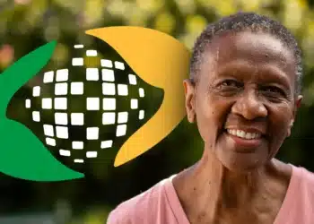 Senhora sorrindo com o símbolo do INSS ao fundo, representando o processo de prova de vida online.