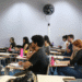 Estudantes sentados em sala de aula universitária prestando atenção na aula