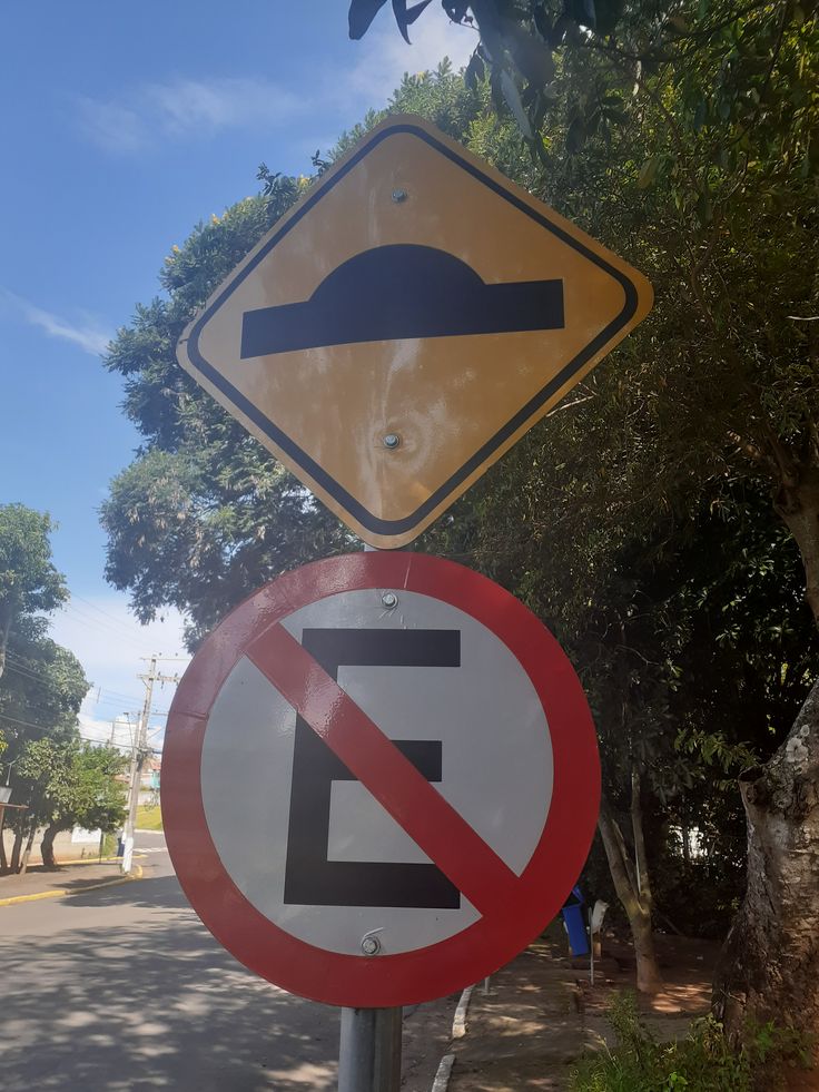 Placas de trânsito indicando a presença de um quebra-mola (lombada) e proibição de estacionar.