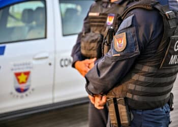 Dois agentes da Guarda Civil Municipal de Vitória próximos a viatura oficial com uniforme preto