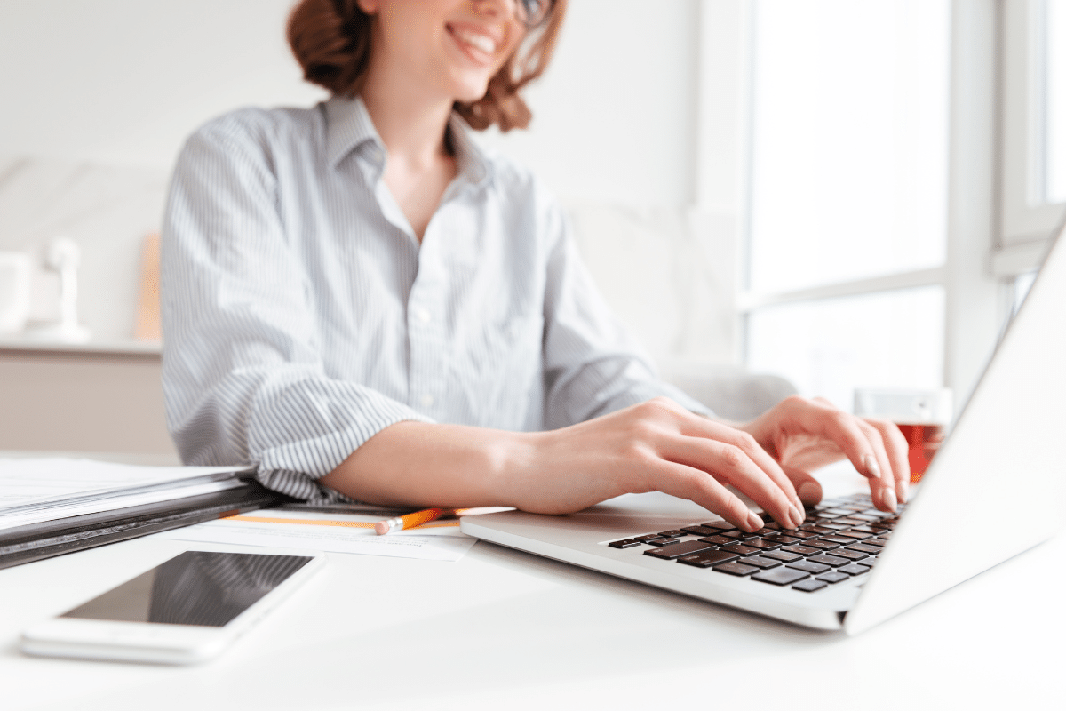 Mulher digitando no notebook em ambiente de trabalho moderno