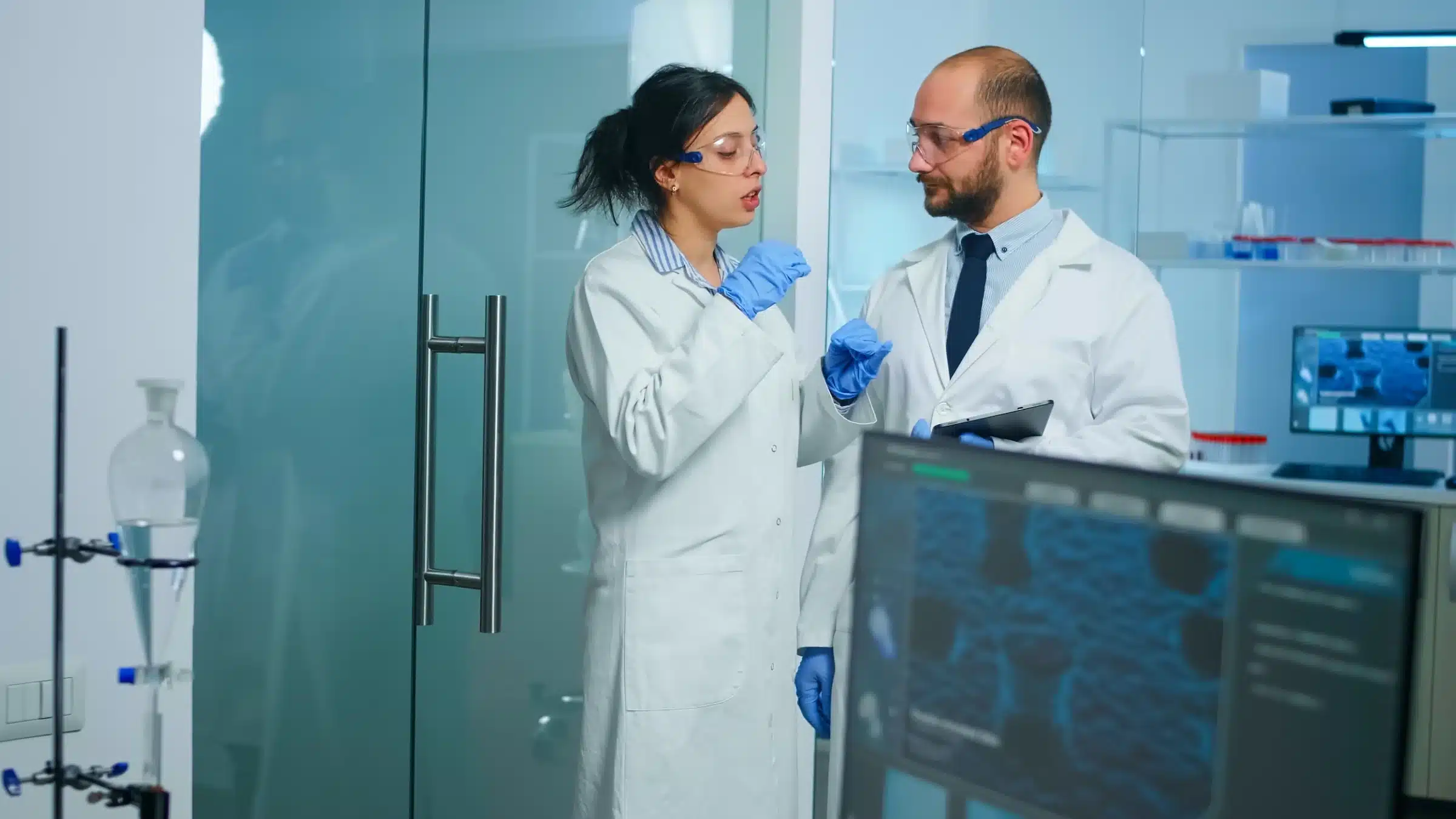 Profissionais de saúde e tecnologia discutindo inovações em laboratório com dispositivos digitais.
