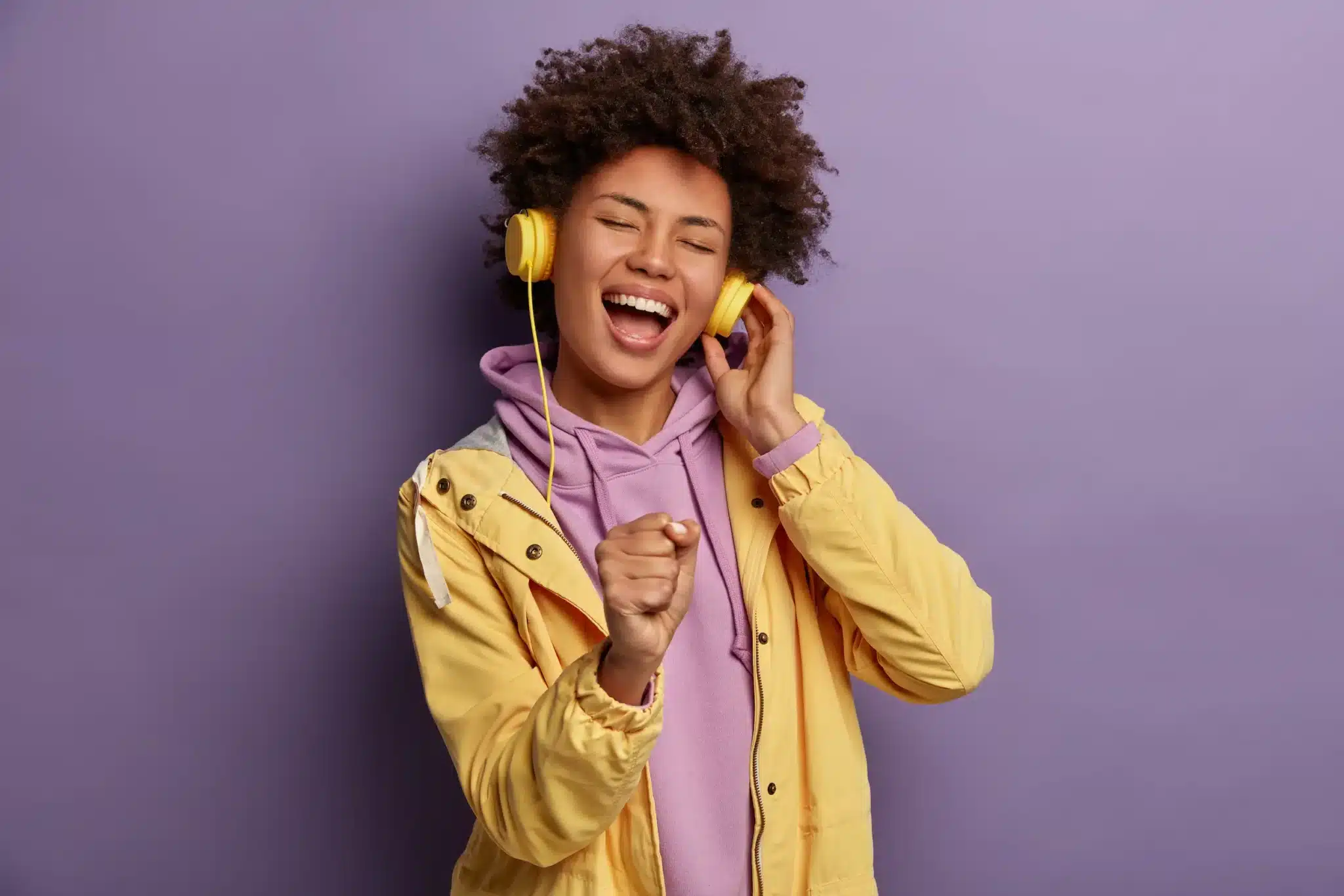 Prazer musical e dopamina Jovem sorridente canta e se diverte ouvindo música com fones de ouvido amarelos