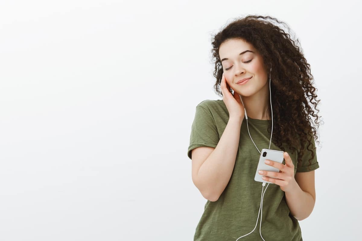 Mulher concentrada ouvindo música no celular com fones de ouvido
