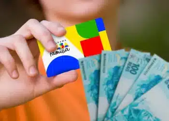 Cartão do Bolsa Família e cédulas de 100 reais, representando o pagamento de R$ 600 em outubro conforme número final do NIS.