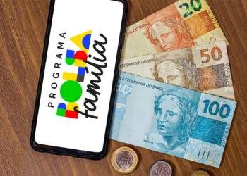 Imagem ilustrativa sobre o pagamento do Bolsa Família de outubro, com cédulas de reais e o logo do programa exibido no celular.