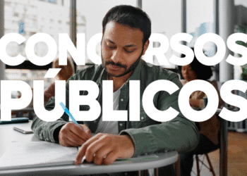 Homem escrevendo em uma mesa de estudos, com foco em concursos públicos.