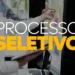 Pessoas em ambiente de trabalho com laptop e papéis realizando processo seletivo com post-its