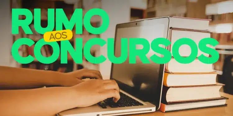Pessoa digitando no computador com livros empilhados ao lado, representando a preparação para concursos públicos.