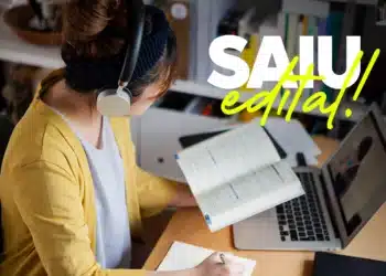 Candidata com fones de ouvido estudando edital de concurso legislativo em ambiente doméstico