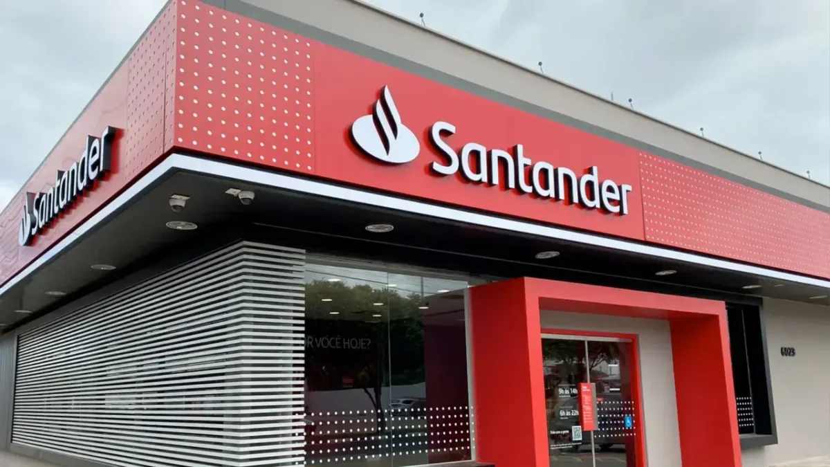 Imagem de uma agência do Santander, destacando a fachada moderna, com o logo e o convite para novas oportunidades de trabalho. Vagas abertas até 15 de outubro.
