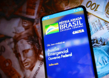 Governo cobra devolução do auxílio emergencial para 4,6 mil brasileiros com celular e notas de real ao fundo