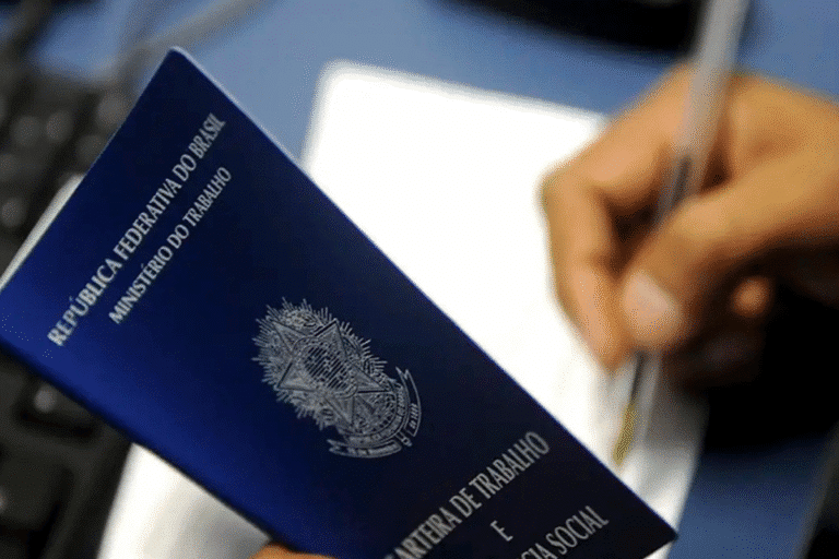 Carteira de Trabalho da República Federativa do Brasil sendo segurada enquanto uma pessoa escreve ou assina