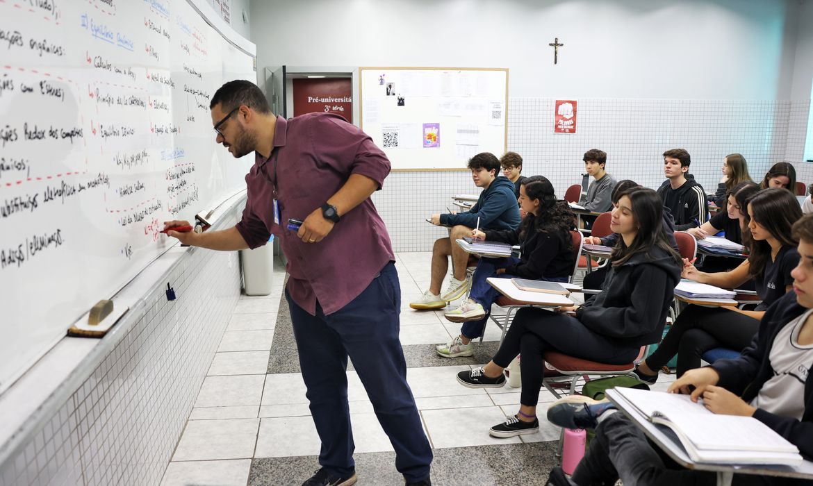 Professor ensinando em sala de aula, com alunos atentos, representando os profissionais que podem solicitar a Carteira Nacional do Docente.