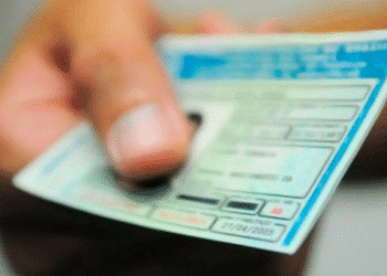 Mão segurando uma Carteira Nacional de Habilitação do Brasil em close desfocado