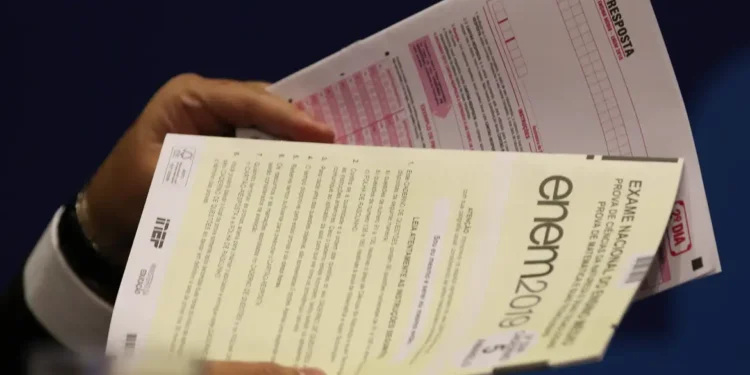 Mãos segurando prova do ENEM 2019 junto com cartão-resposta para exame nacional do ensino médio