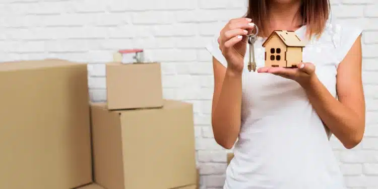 Mulher segurando uma miniatura de casa e chaves, simbolizando novas regras de financiamento imobiliário.