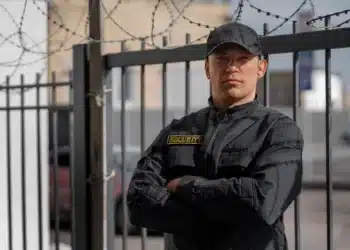 Guarda municipal em frente a grade de segurança com uniforme preto.