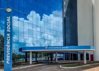 Fachada do INSS com céu refletido na parede de vidro, representando o atendimento do INSS em mutirão.