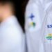 Médicos com jaleco do SUS, representando o programa Mais Médicos para o Brasil, enquanto o Enamed 2025 é realizado.