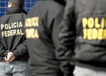 Agentes da Polícia Federal com homem algemado, ilustrando operação contra fraudes em concursos como CNU, Caixa e Banco do Brasil.