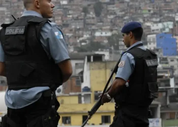 Grupo de policiais penais reunidos em protesto com bandeiras de estados e a do Brasil, ambiente interno com pessoas em atitude de apoio