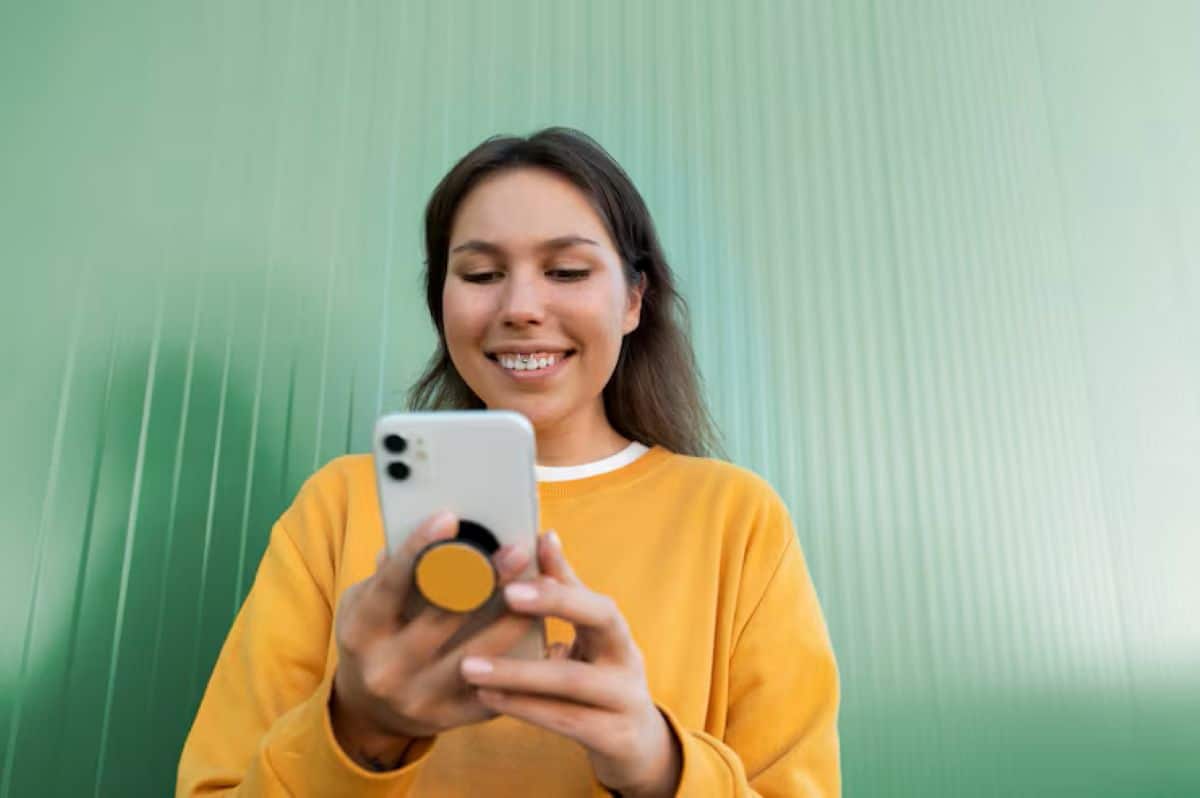 Jovem sorri enquanto usa o celular, representando o novo recurso do WhatsApp com inteligência artificial.