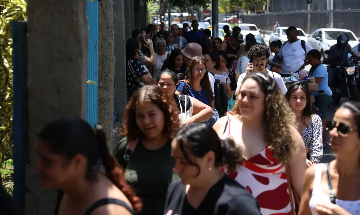 Multidão de candidatos caminhando em fila para entrar no local de prova, representando a alta adesão à Prova Nacional Docente (PND).