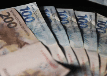 Cédulas de dinheiro em leque representando a primeira parcela do 13º salário depositada na conta.