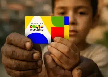 Cartão do Programa Bolsa Família sendo segurado por mãos de um adulto e de uma criança.