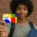 Criança segurando o cartão do programa Bolsa Família, com fundo de tijolos, representando os pagamentos do benefício de novembro.